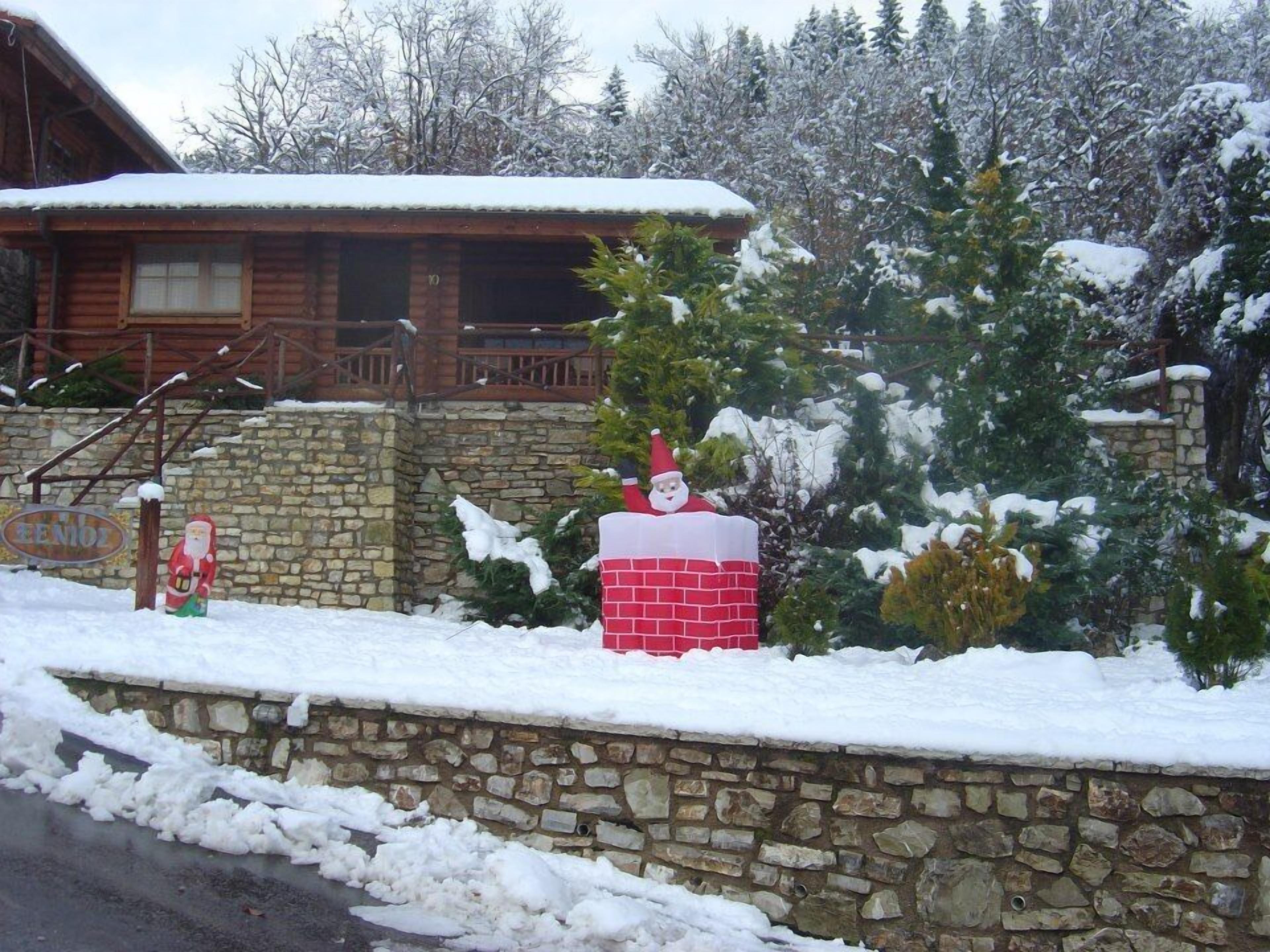 A stone wall with a wooden cabin in the background.