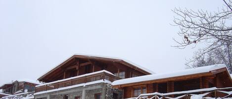 A stone building with wooden balconies and a snow-covered roof.