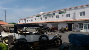 Un coche antiguo estacionado frente a un edificio con un letrero que dice "Le Mareuilais Restaurant" y "Hôtel".
