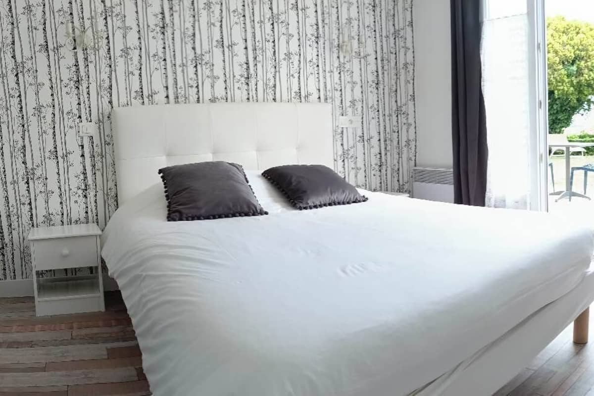 Un dormitorio con una cama grande, una silla y un escritorio.
