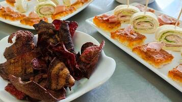 A variety of appetizers including skewered meats, rolled sandwiches, and small bites on white plates.