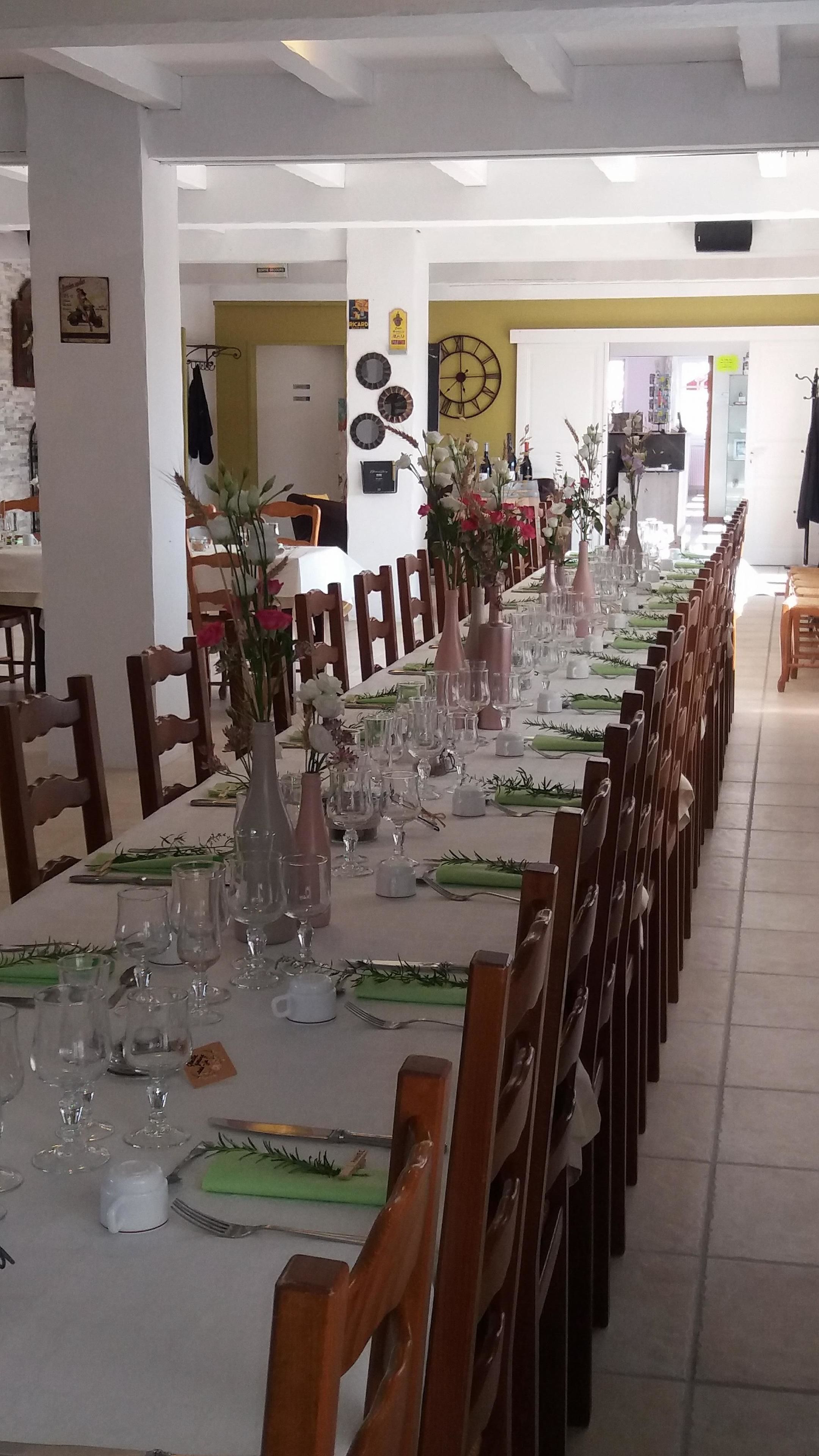 A long dining table set for a meal with chairs on both sides.