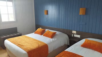 A hotel room with two beds, each with an orange bedspread and pillows, a wooden headboard, a bench, and a window with blinds.