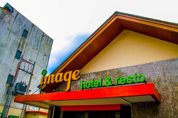 A hotel sign with the name "Image Hotel & Resto" and a modern architectural design.