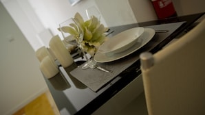 A dining table set with plates, cutlery, and a glass. - Azores Horta Apartments (Horta)