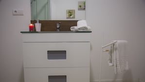 A modern bathroom with a glass-top sink, two drawers, a towel rack, and a mirror. - Azores Horta Apartments (Horta)