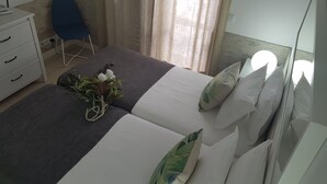 Um quarto bem arrumado com uma cama, uma mesinha de cabeceira, uma cadeira e uma janela com cortinas.