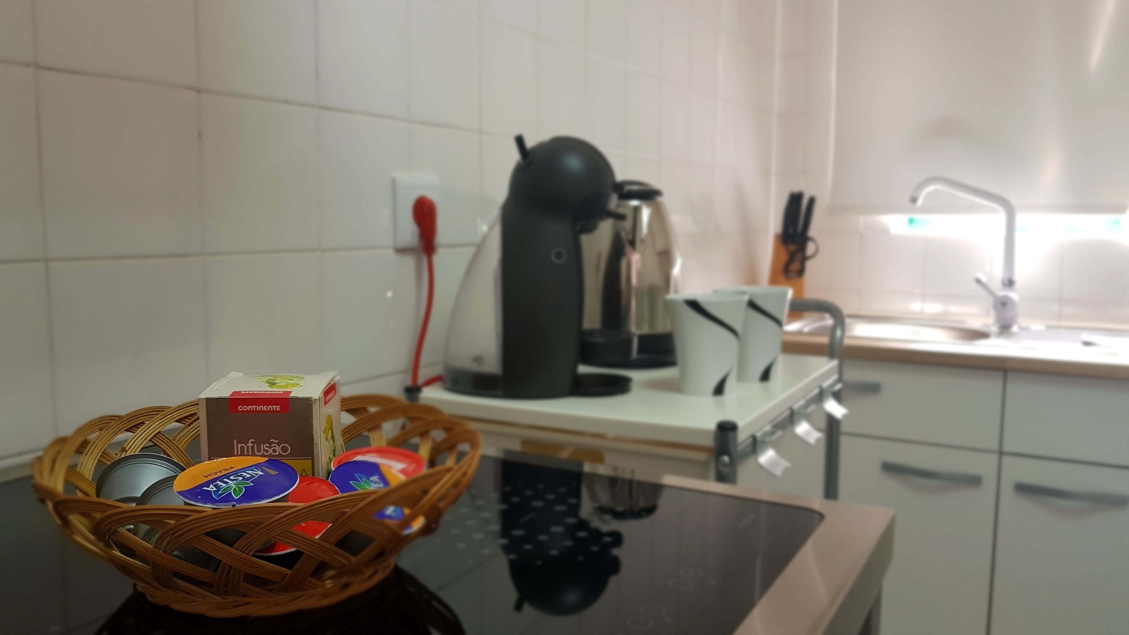 A kitchen with a coffee machine, a basket of items, and a sink.
