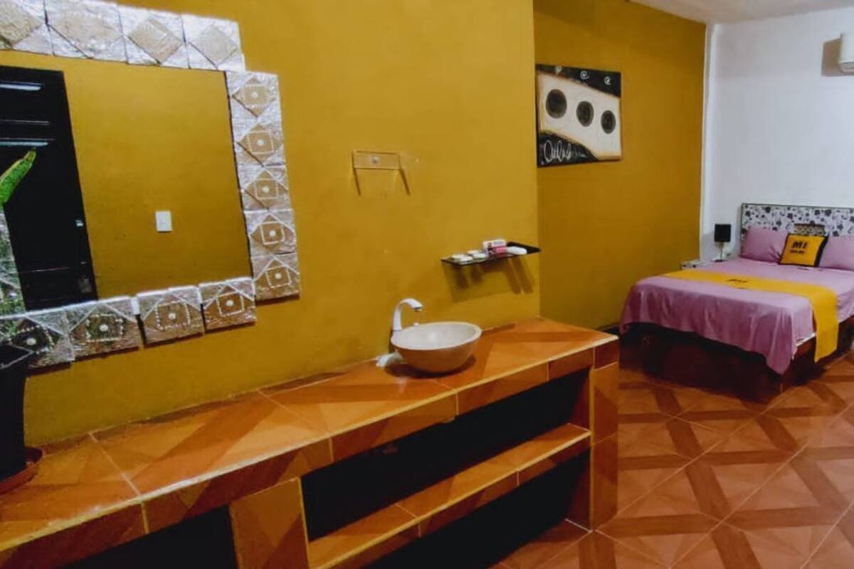 A bedroom with a bed, bedside tables, a mirror, and a sink.