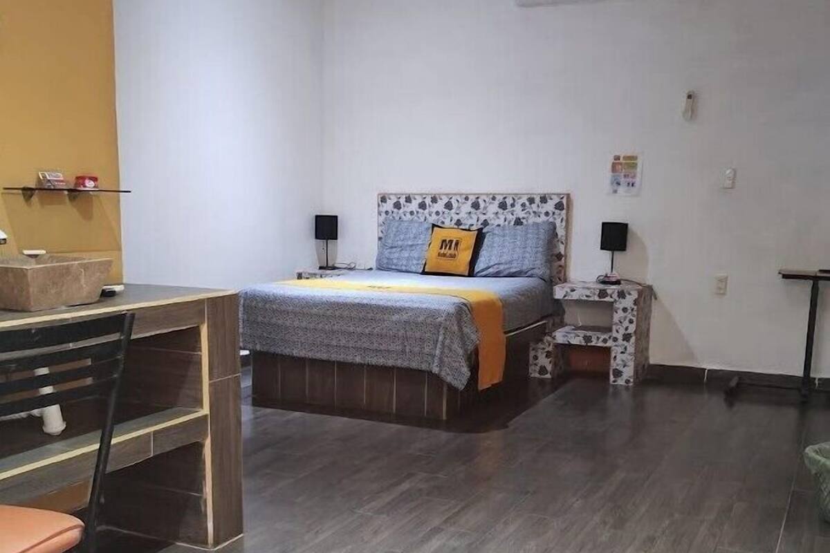A bedroom with a bed, bedside tables, a desk, and a chair.