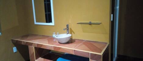 A bathroom with a white sink, a mirror, and a shelf above the sink.