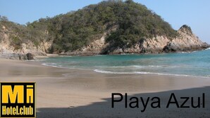 Una playa con un cartel que dice "Playa Azul" y el logotipo de "Mi Hotel.Club".