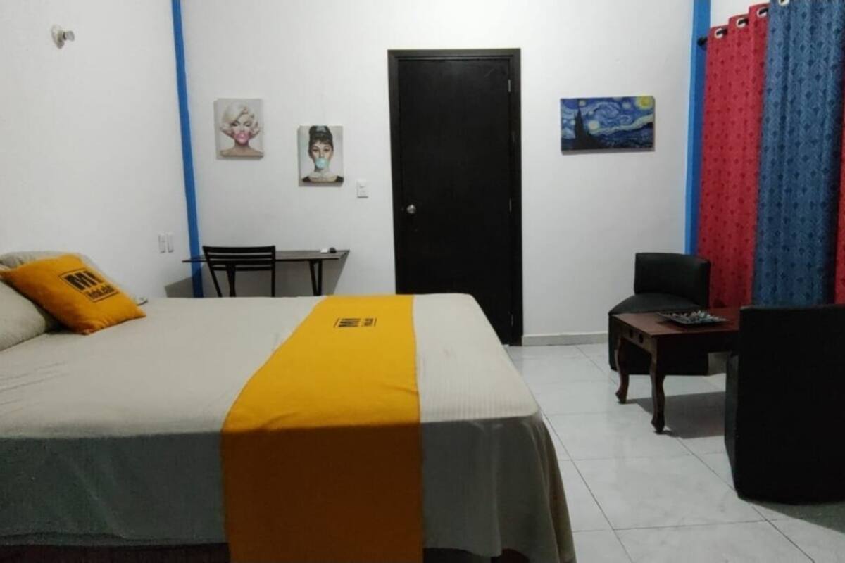 A bedroom with a bed, a desk, and a chair.