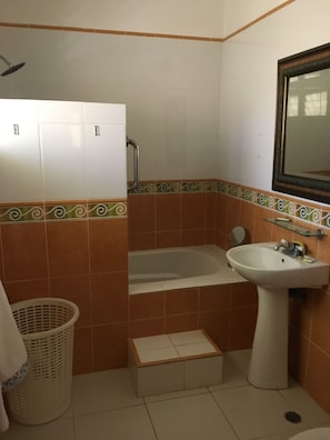 Une salle de bain avec une baignoire, un lavabo, un miroir et un panier à linge.
