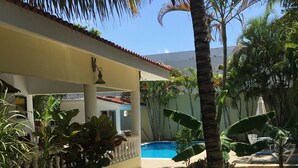 Un espace piscine doté d’une terrasse carrelée, de palmiers et de plantes en pot.
