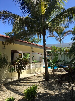 A building with a tiled roof, a covered patio area, and a pool.