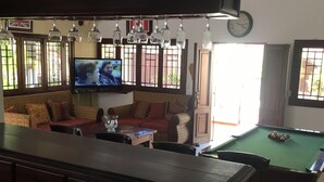 Un salon confortable avec une table de billard, un ensemble de canapés et un téléviseur.