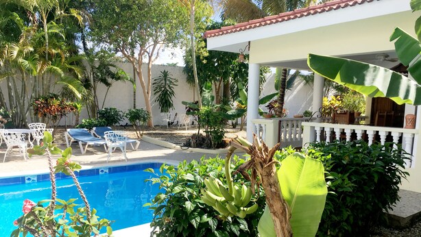 Un espace piscine avec des chaises longues et une pergola.