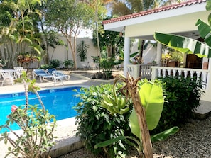 Un espace piscine avec des chaises longues et une pergola.
