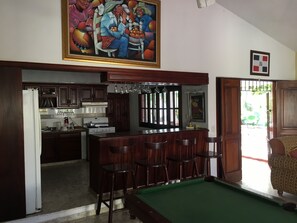 A kitchen with wooden cabinets, a refrigerator, a stove, and a bar area with stools.