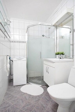 A modern bathroom with a glass-enclosed shower, a white sink, and a vanity with a mirror.