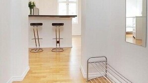 A modern kitchen with a central island, two bar stools, and a large mirror on the wall. - Modern Apartment In The City Center (Bergen)