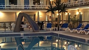 A pool area with lounge chairs and a large decorative sculpture.