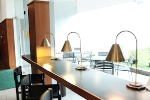 A modern kitchen with a long countertop, two pendant lights, and a view of the outdoor patio area.