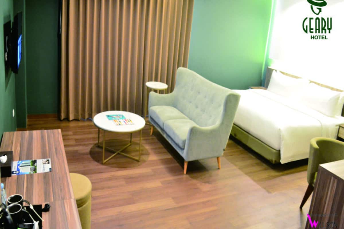 A hotel room with a sofa, a bed, a small round table, and a television.