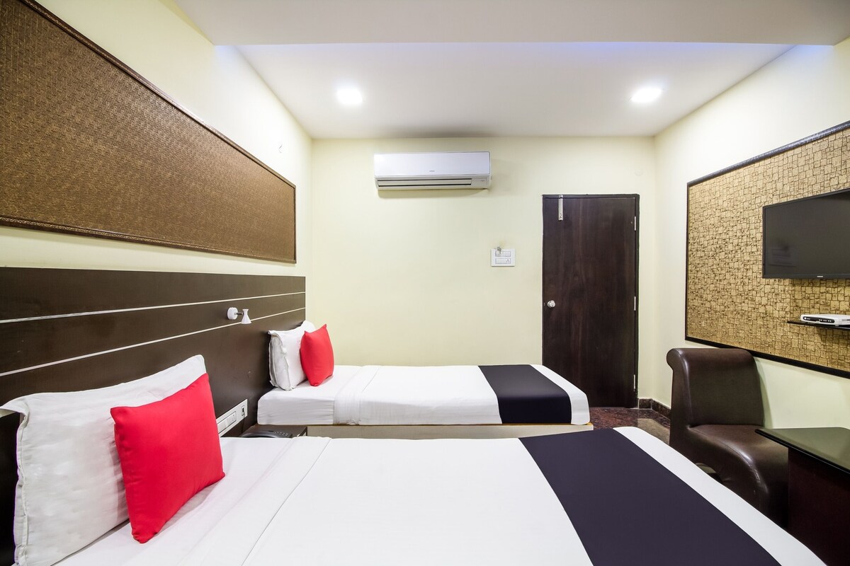 A hotel room with two beds, a TV, an air conditioner, and a door.