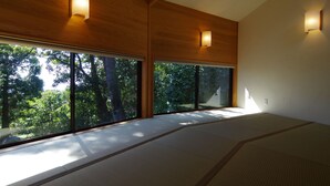 Een kamer met tatami matten, grote ramen en houten wanden.