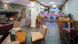Un interior acogedor con chimenea de piedra, muebles de madera y una zona de bar.