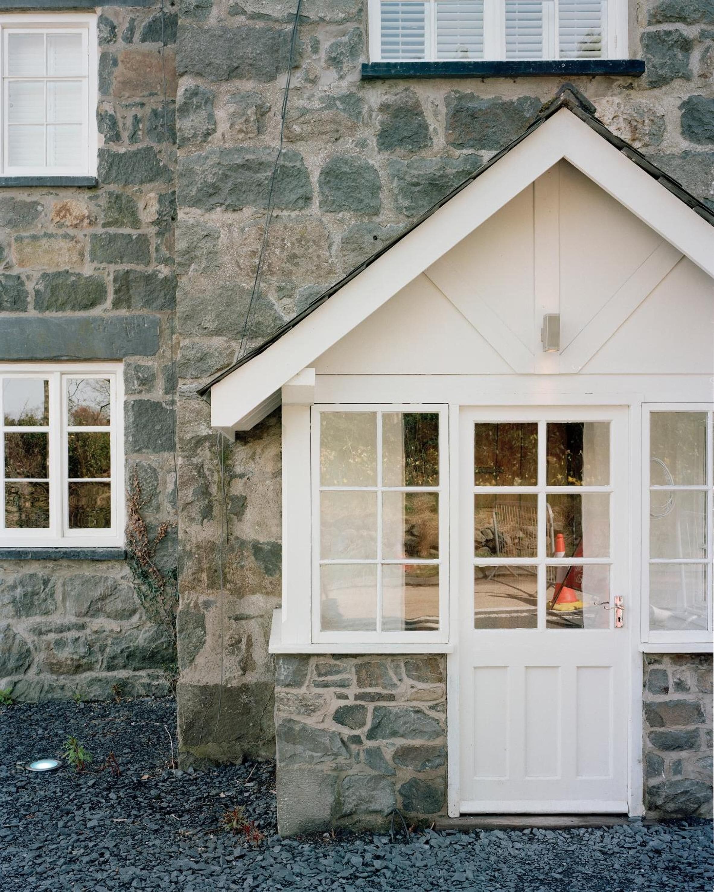 A stone building with a white door and windows.