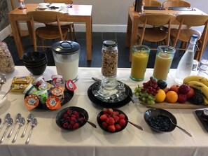 Een ontbijtbuffet met diverse producten, zoals fruit, ontbijtgranen en drankjes.
