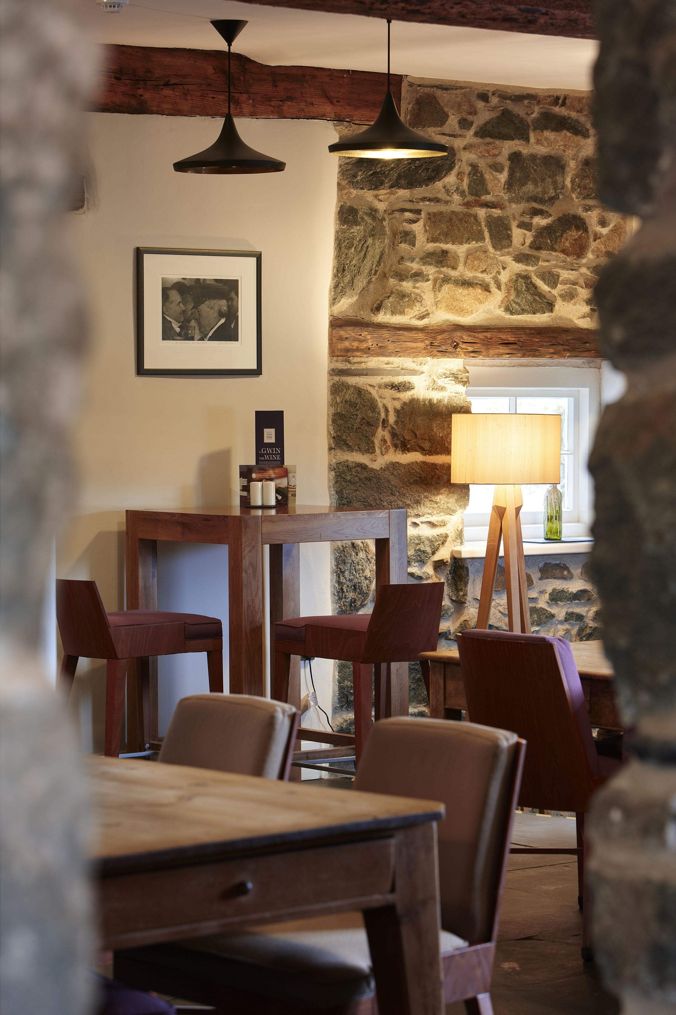 A rustic dining area with a stone wall, wooden table, and chairs.