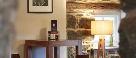 A rustic dining area with a stone wall, wooden table, and chairs.