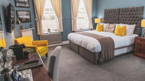 Un dormitorio con una cama grande, un escritorio con una silla, un sillón amarillo y un radiador.