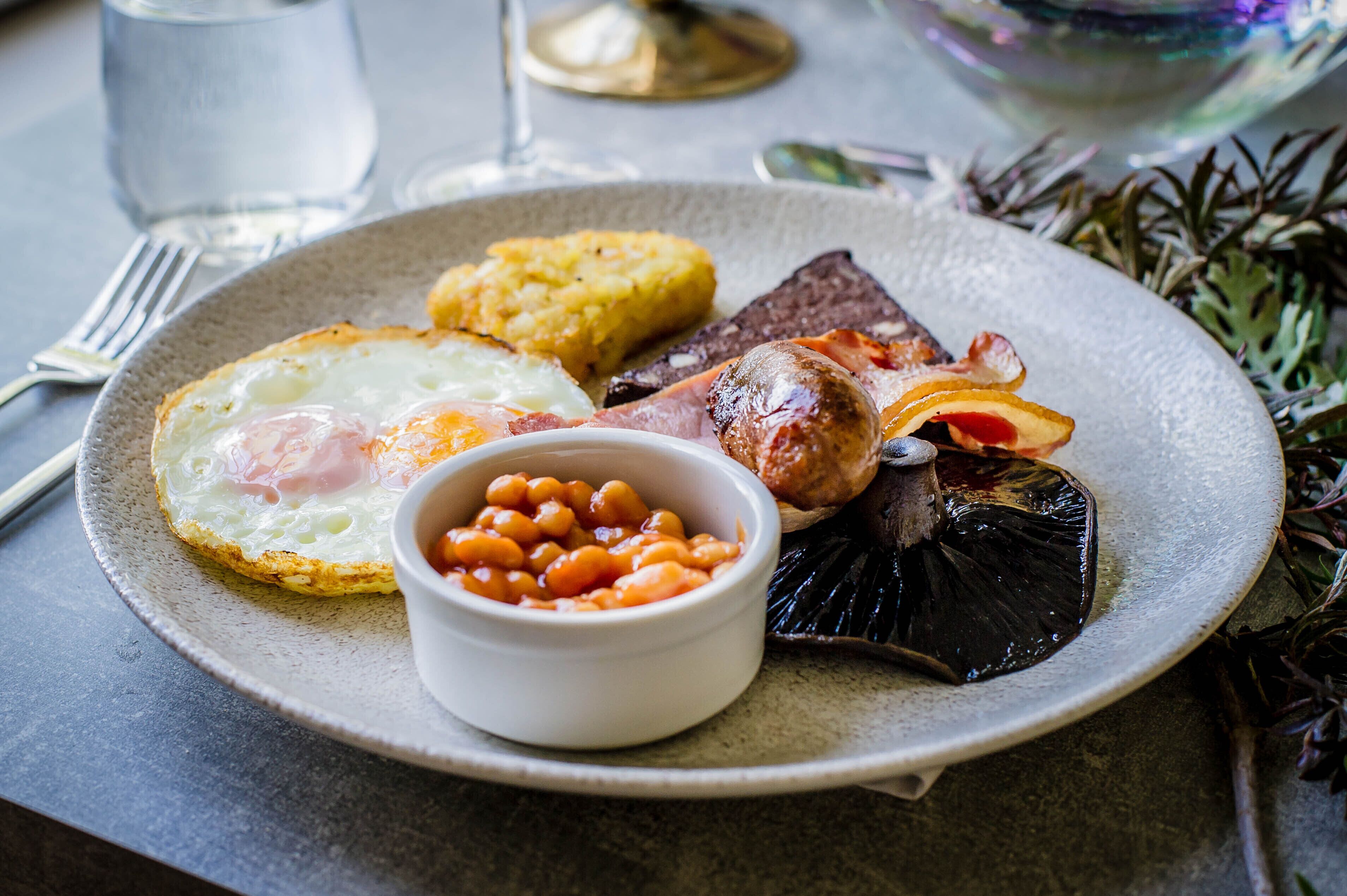 Un plato con huevos, frijoles y diferentes carnes, posiblemente un desayuno o un almuerzo.