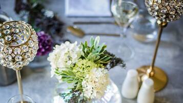 A dining table with a plate of food, a vase with flowers, and a decorative lamp.