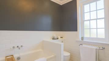 A modern bathroom with a bathtub, toilet, and a window.