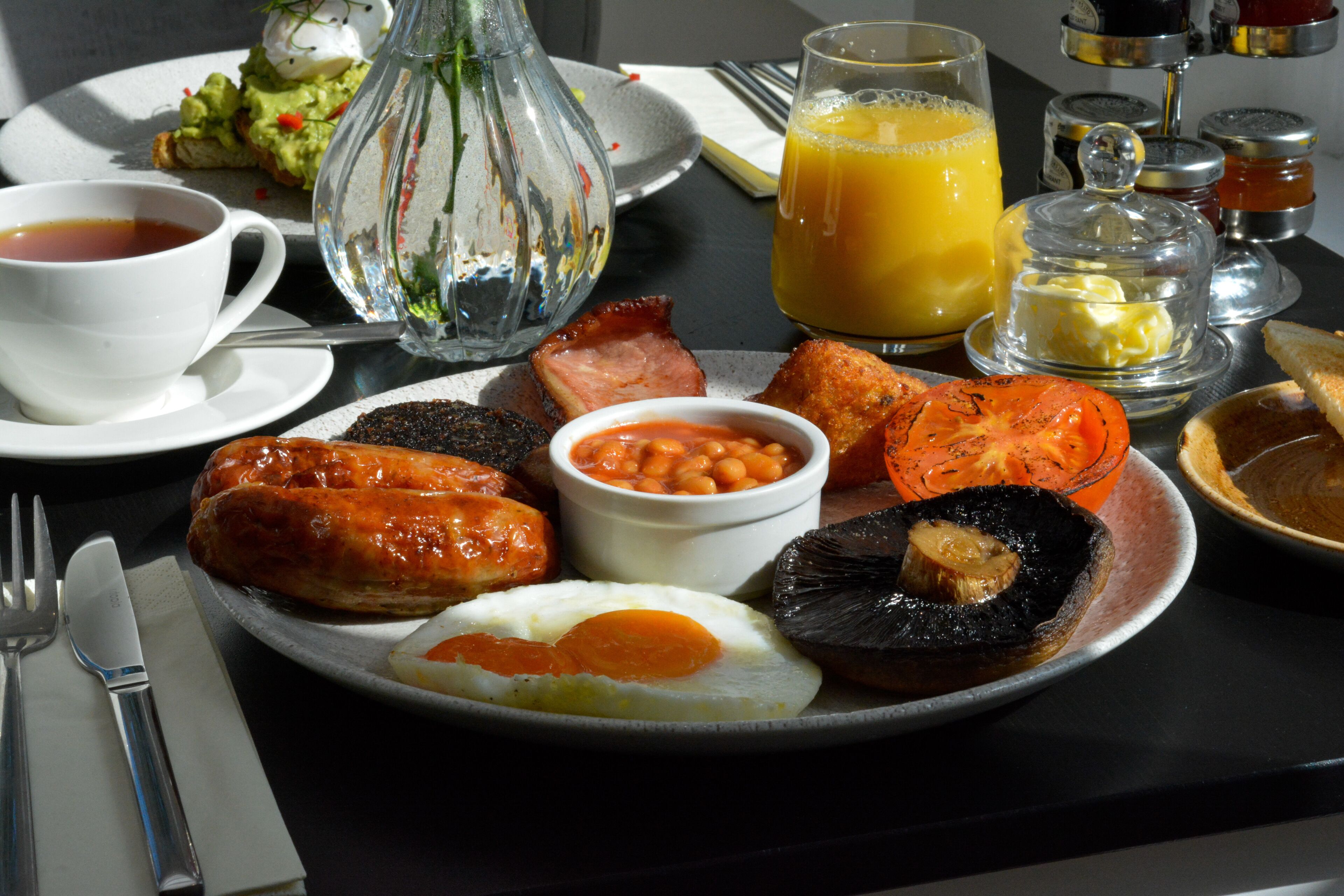 A breakfast plate with eggs, sausages, beans, tomatoes, and toast.
