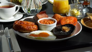 A breakfast plate with eggs, sausages, beans, tomatoes, and toast.