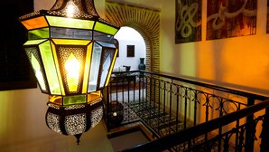 A staircase with a wrought iron railing, a hanging lantern, and a wall with an archway and artwork. - Dar Dada Mouss (Marrakech)