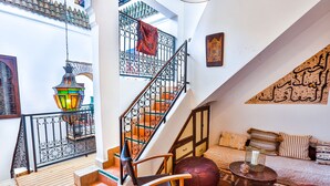A spacious living area with a staircase, a sofa set, a wooden chair, a patterned rug, and a decorative lantern. - Dar Dada Mouss (Marrakech)