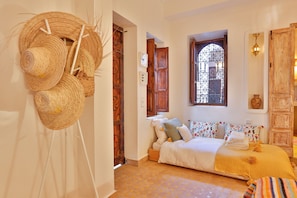 A cozy bedroom with a bed, pillows, and a window with a decorative iron grille. - Dar Dada Mouss (Marrakech)