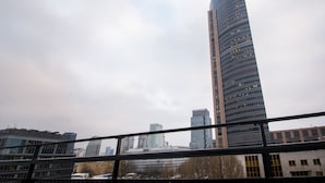 Un rascacielos alto y moderno con una parte superior curva, rodeado de otros edificios.