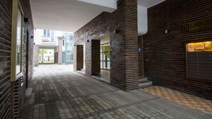 Un pasillo con paredes de ladrillo, piso a cuadros y una entrada visible a otro edificio.