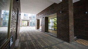 Un pasillo interior con paredes de ladrillo, suelo de baldosas y amplias ventanas.