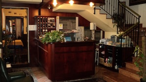 Een ruime woonkamer met een houten bar, een eettafel en een trap naar een hoger gelegen verdieping.