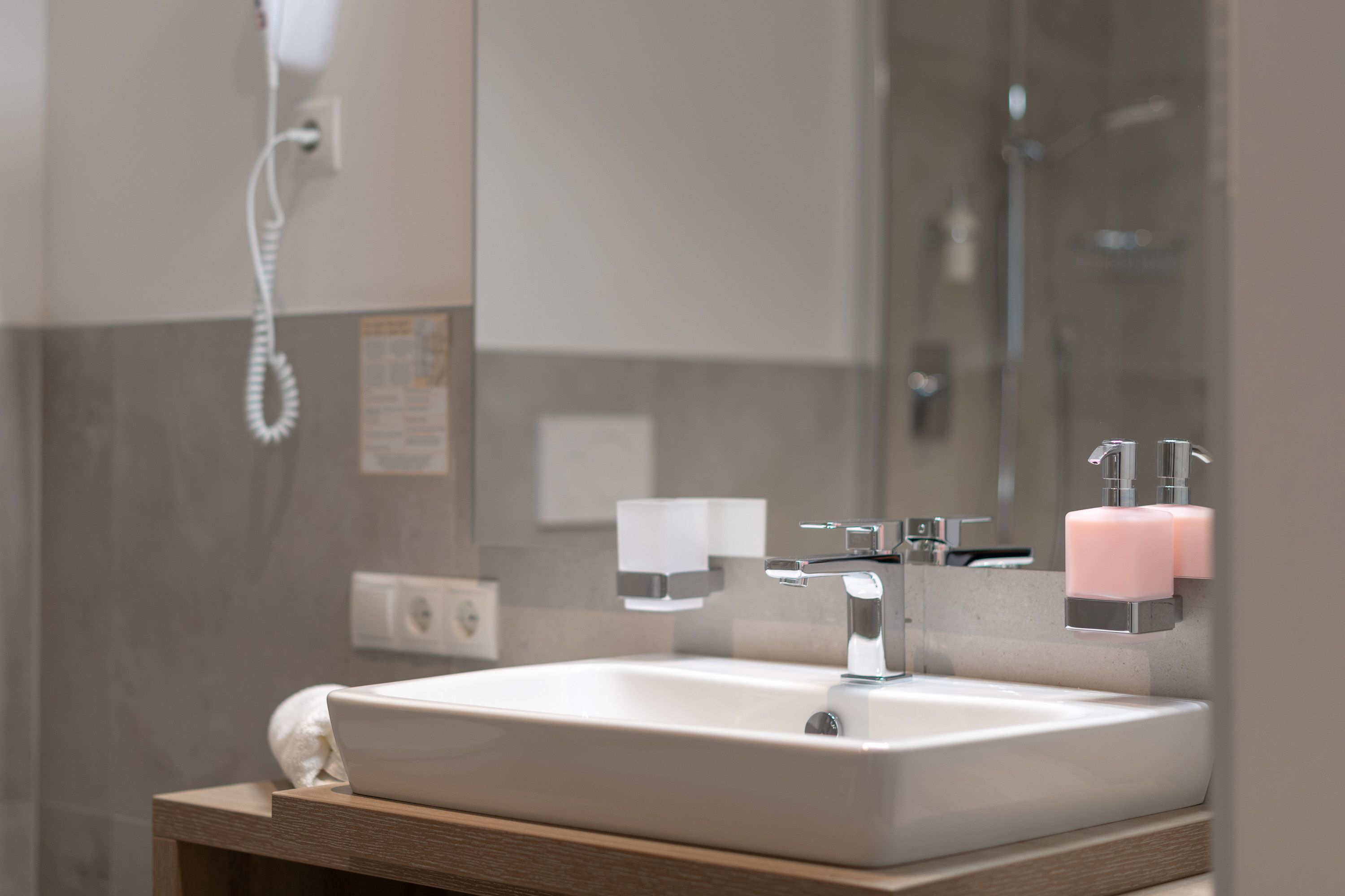 Une salle de bain avec un lavabo blanc, un miroir et un espace douche.